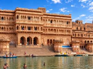 Devotees bathing and riding wooden boats along the sacred sandstone ghats of the Yamuna River in Vrindavan.