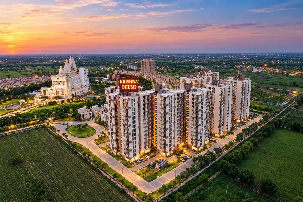 Krishna Bhumi from the air at sunset: apartment towers and tree-lined avenues beside the temple, with open fields beyond